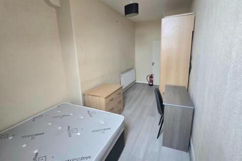 A modest student bedroom featuring a bed with s...