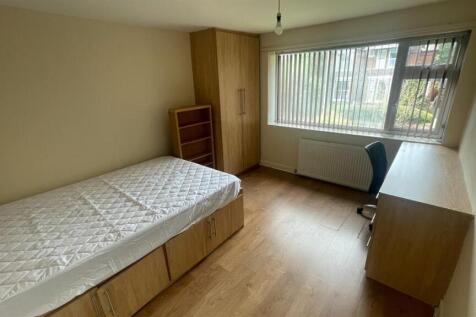 A tidy, well-lit single bedroom featuring a bed...