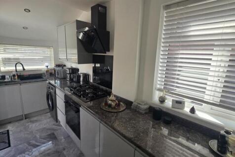 A modern kitchen with a sleek countertop, stain...