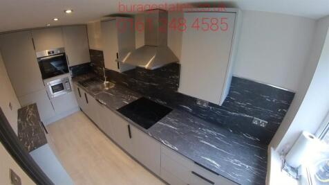 Modern kitchen featuring sleek dark countertops...