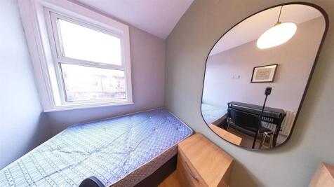 A compact bedroom featuring a single bed and a ...