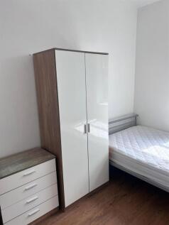 A tidy bedroom featuring a wardrobe, a bedside ...