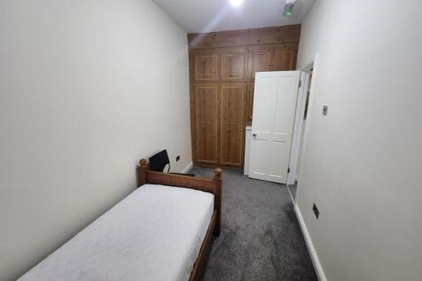 A tidy and simple student bedroom featuring a s...