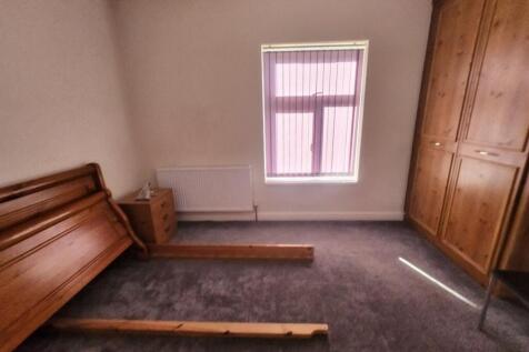 A modest bedroom with a single window providing...