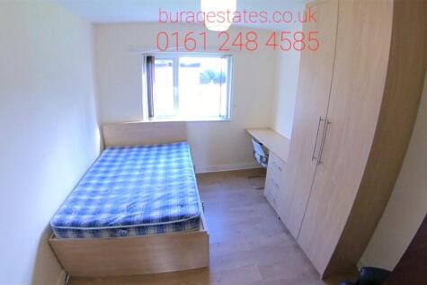 A small, neat single bedroom with a simple bed ...