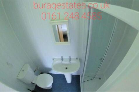 Compact bathroom featuring a clean white toilet...