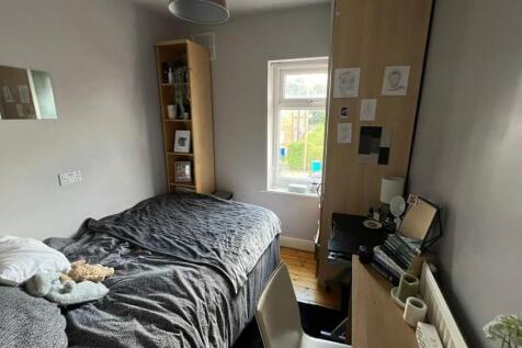 A cozy single bedroom featuring a bed with bedd...