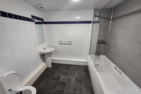 A modern, clean bathroom with a bathtub, shower...