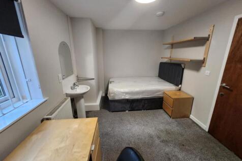 A well-lit, tidy student bedroom featuring a si...