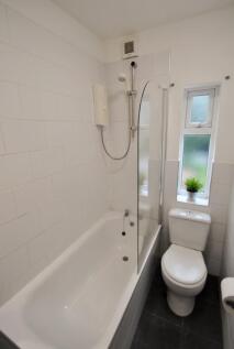 Bright and clean bathroom suite featuring a whi...