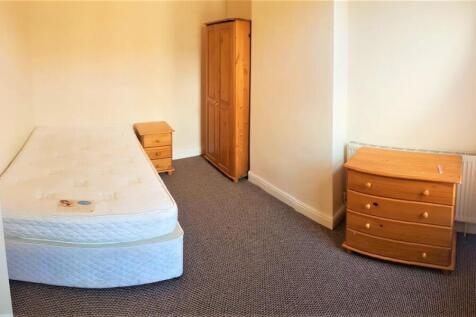 A modest student bedroom featuring a mattress o...