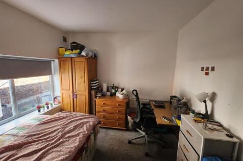 A cozy student bedroom featuring a single bed, ...