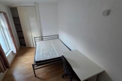 A tidy bedroom featuring a standard bed frame w...