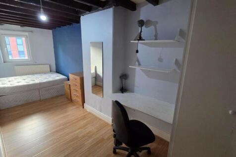 A well-lit bedroom featuring a comfortable bed,...