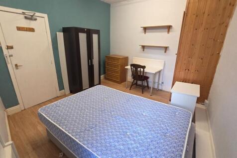 A cozy single bedroom featuring a simple bed se...