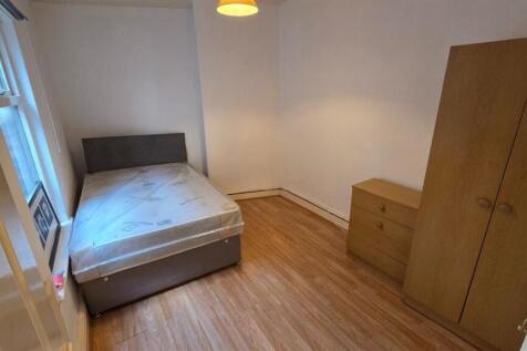 A cozy single bedroom with a simple bed, wooden...