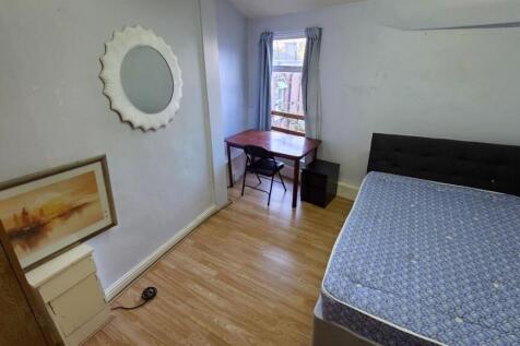 A cozy single bedroom with a simple bed, a wind...