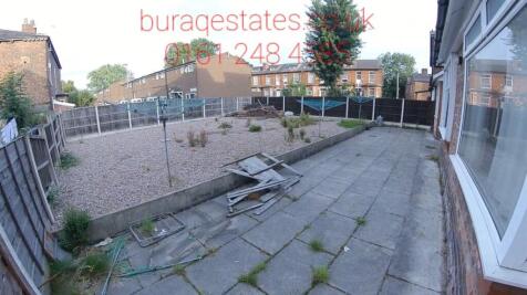 A spacious, sunlit garden area featuring a pave...