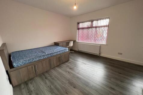 A spacious and well-lit single bedroom featurin...