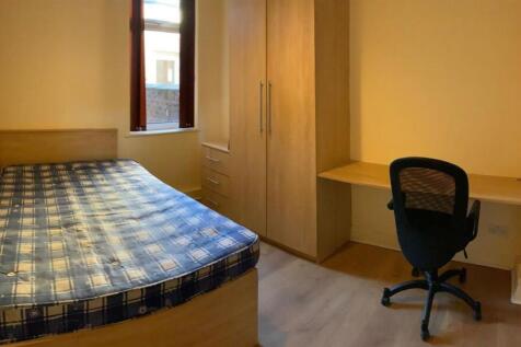 A well-lit single bedroom featuring a comfortab...