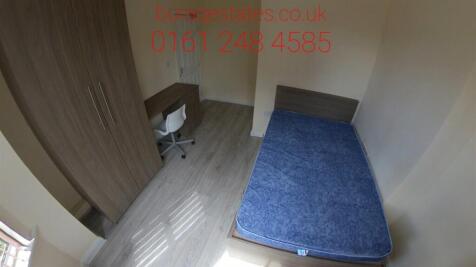 A small, basic room featuring a single bed with...