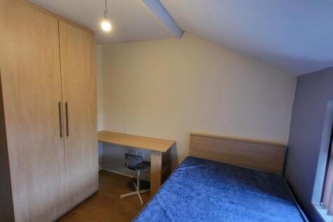 A tidy, well-lit bedroom featuring a bed, woode...