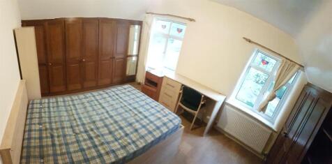 A well-lit, tidy bedroom featuring a comfortabl...