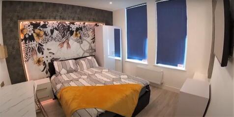 A well-lit bedroom featuring a comfortable doub...