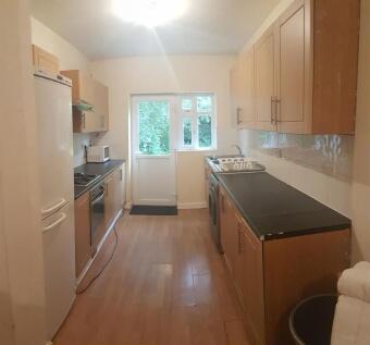 A well-lit, tidy kitchen with wooden cabinets a...