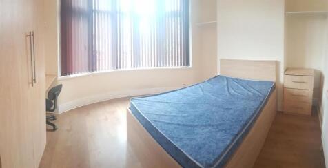 A cozy student bedroom featuring a single bed w...