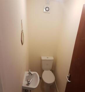 A compact bathroom featuring a toilet and a sma...