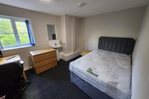 A clean and bright bedroom featuring a comforta...