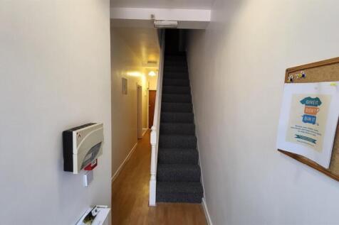 A clean and tidy hallway with wooden flooring a...