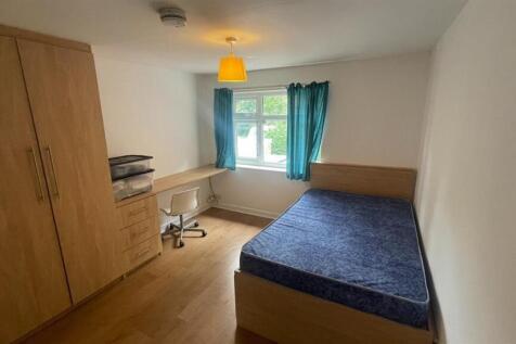 A cozy single bedroom featuring a spacious bed,...