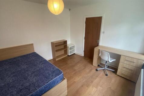 A clean and well-lit bedroom with a large bed a...