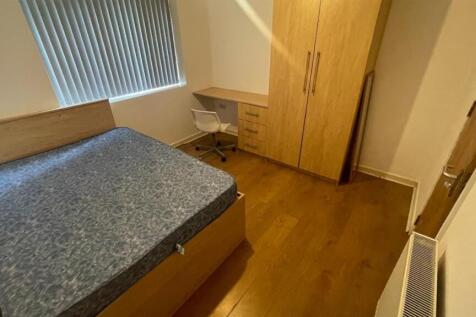 A cozy single bedroom featuring a bed with a si...