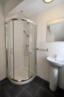 A modern bathroom featuring a curved glass show...