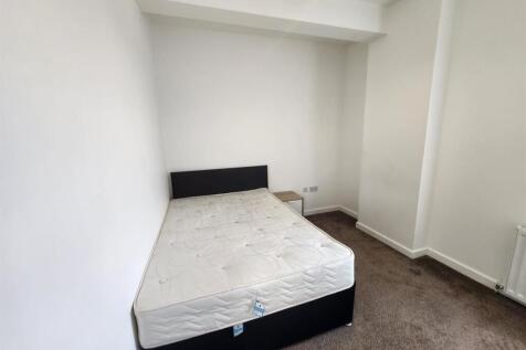 A clean and bright bedroom featuring a bed fram...