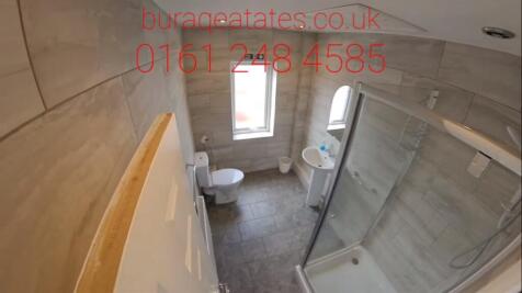 Modern tiled bathroom with a corner glass showe...