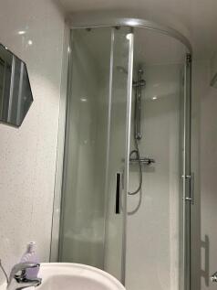 A modern bathroom featuring a curved glass show...