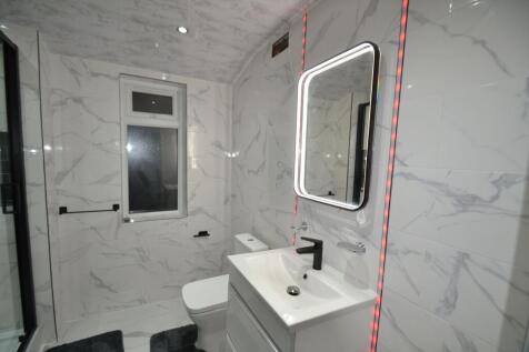 Contemporary fully tiled bathroom with a backli...