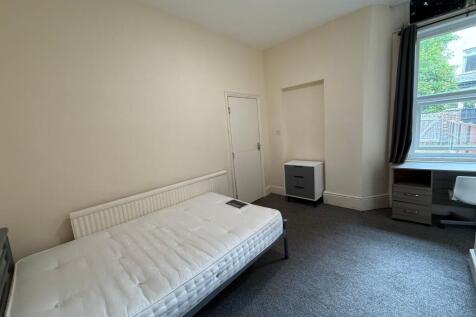 Bright, neutrally decorated bedroom with a comf...