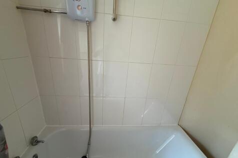 Bright, tiled bathroom with a built-in bathtub ...