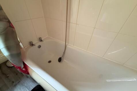 Bright bathroom with a clean white bathtub, til...