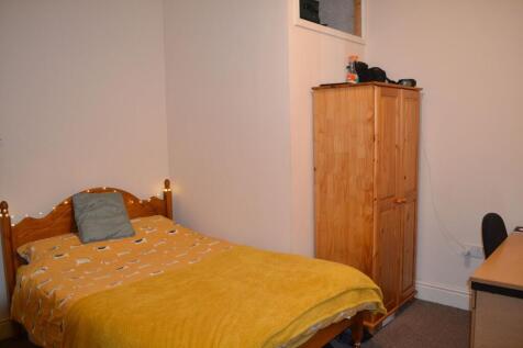 A cozy single bedroom featuring a warm yellow b...