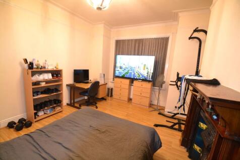Spacious bedroom with wooden floors, a large TV...