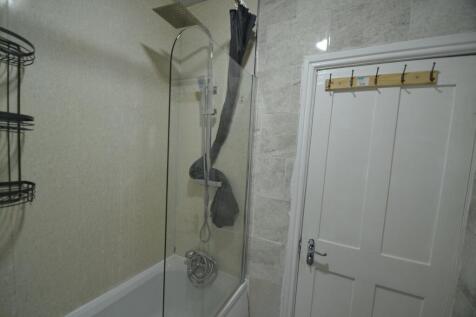 A clean, compact bathroom featuring a shower ar...