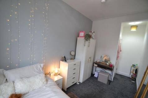 A cozy bedroom featuring a bed with white linen...