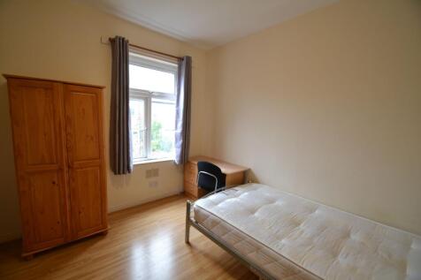 A bright and tidy single bedroom with a wooden ...