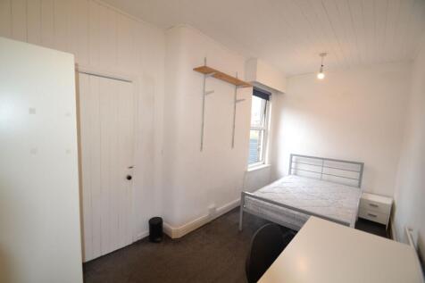 A tidy student bedroom featuring a single bed w...